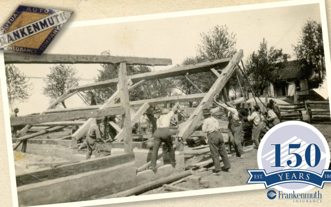 An old black and white photo of many workers lifting the frame of a new building into place.